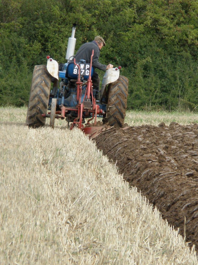 Tractor with two-furrow plow, turning over soil.